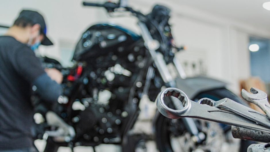 整備スタンドでバイクのエンジン整備を行う整備士の作業イメージ。